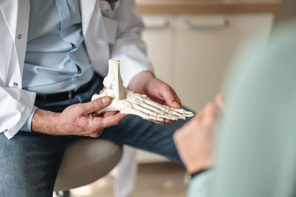 Close up of a general practitioner showing bones of a foot on a skeleton