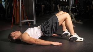 Man performs a hip stretch in a gym environment. 