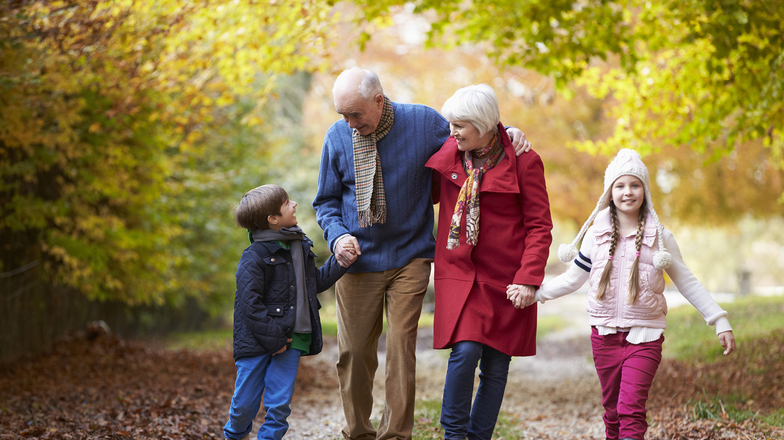 Grandparents walking in the park on a fall day with Grandchildren.